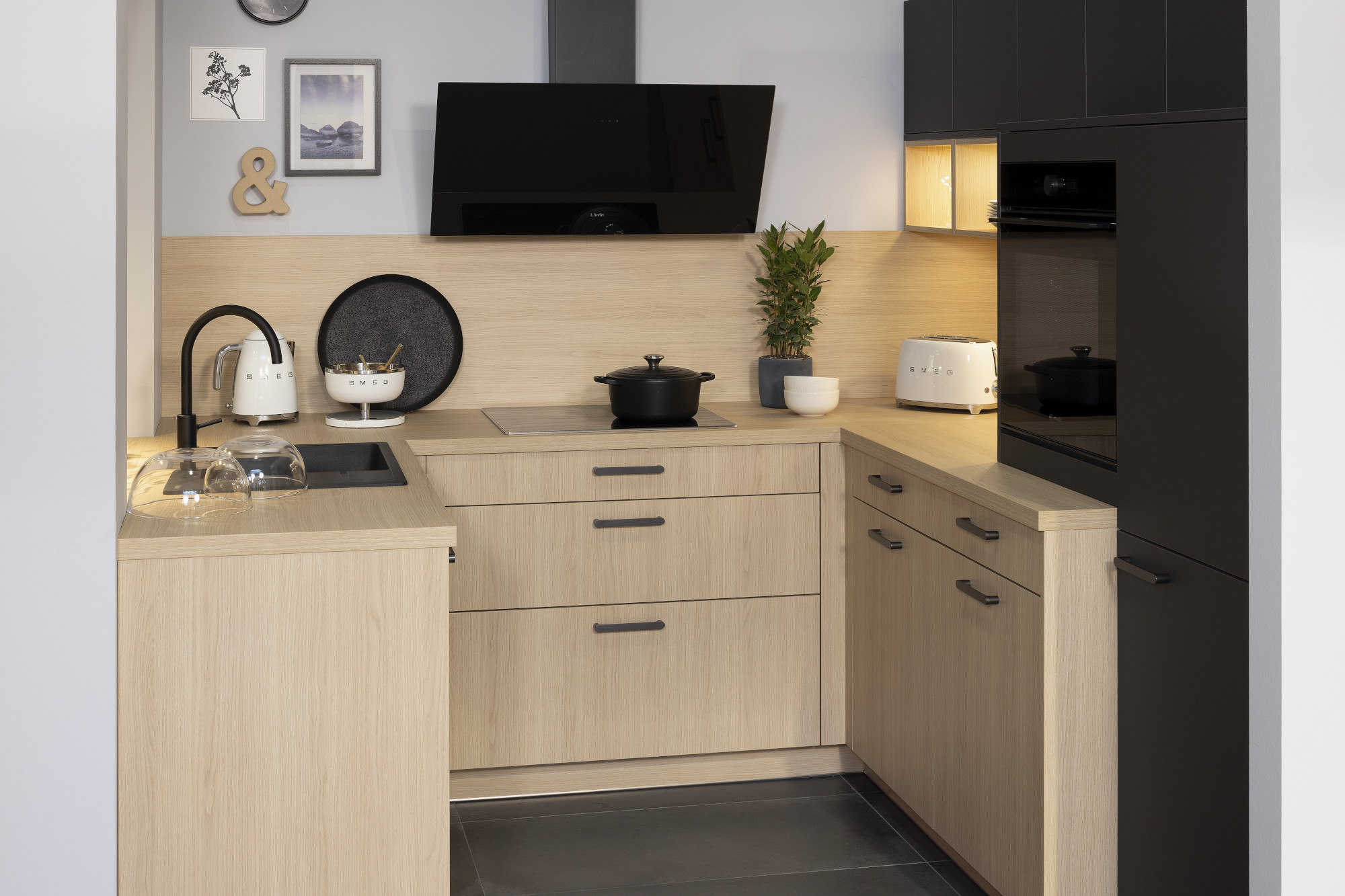 Moderne Eckküche mit hellen Holzfronten, schwarzen Akzenten und Elektrogeräten