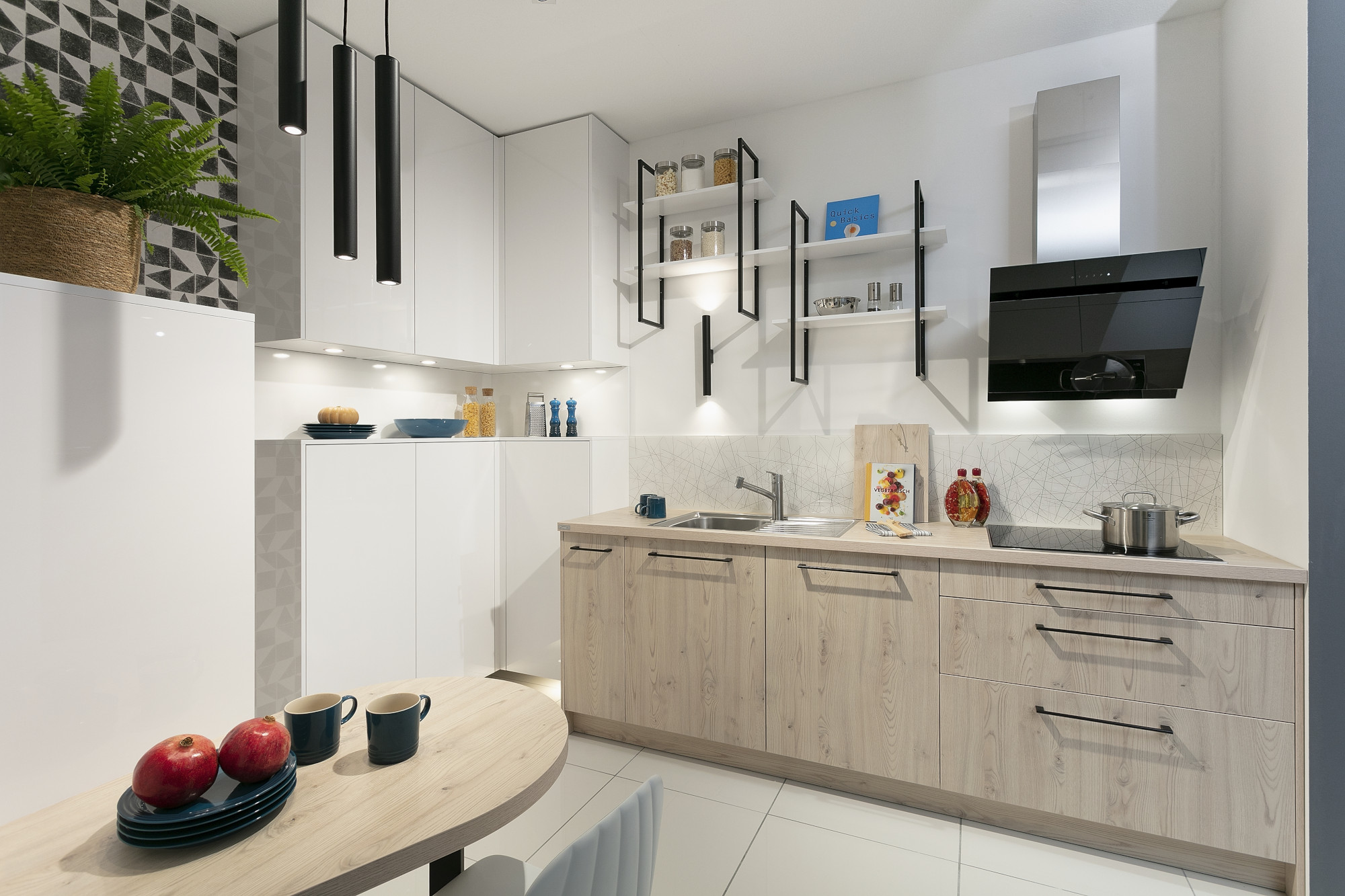 Moderne Küche mit hellem Holz, schwarzen Akzenten und roten Äpfeln auf dem Tisch.