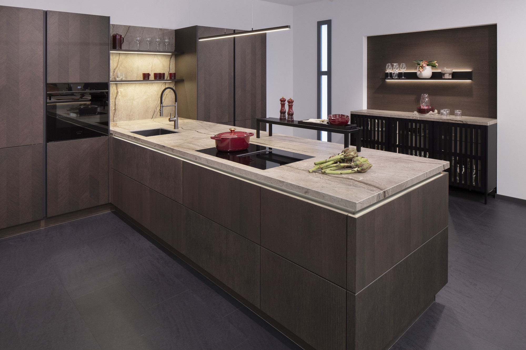 Moderne Küche mit dunklen Schränken, Kochinsel und beleuchteten Regalen