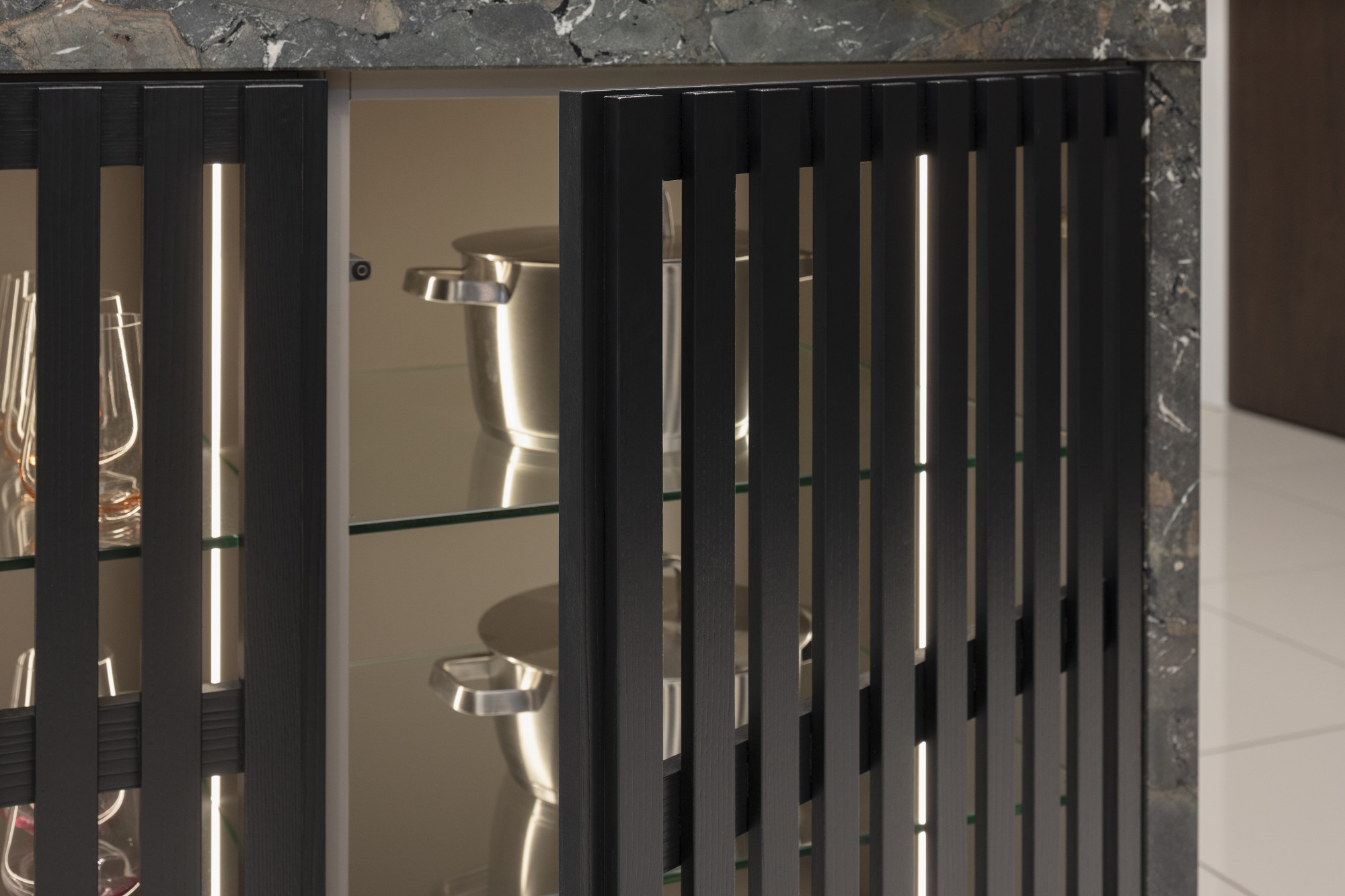 Schwarzer Glasschrank mit Glastüren und Gläsern auf Glasböden.