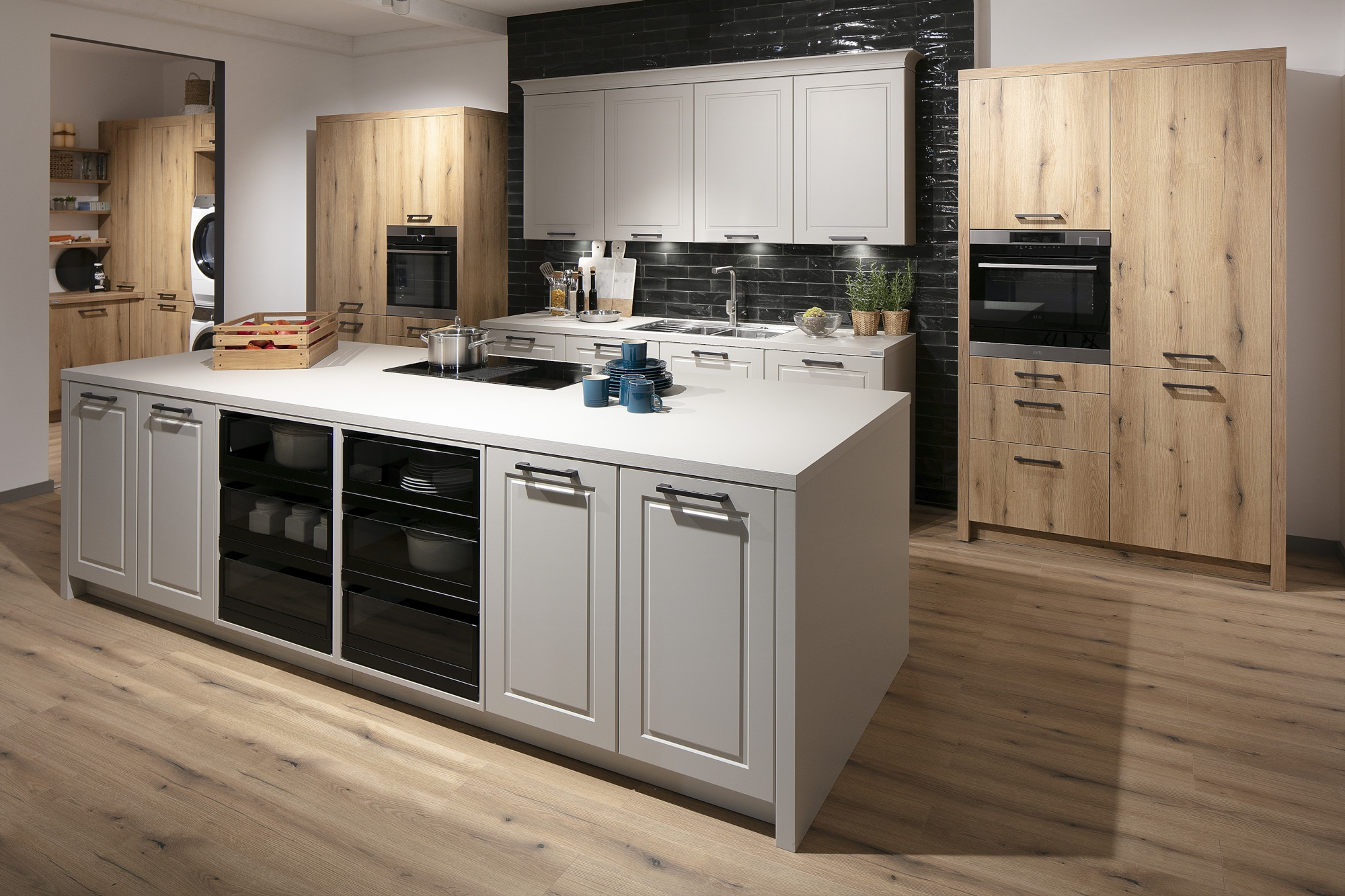 Moderne Küche mit weißer Kochinsel, Holzschränken und schwarzer Fliesenrückwand.