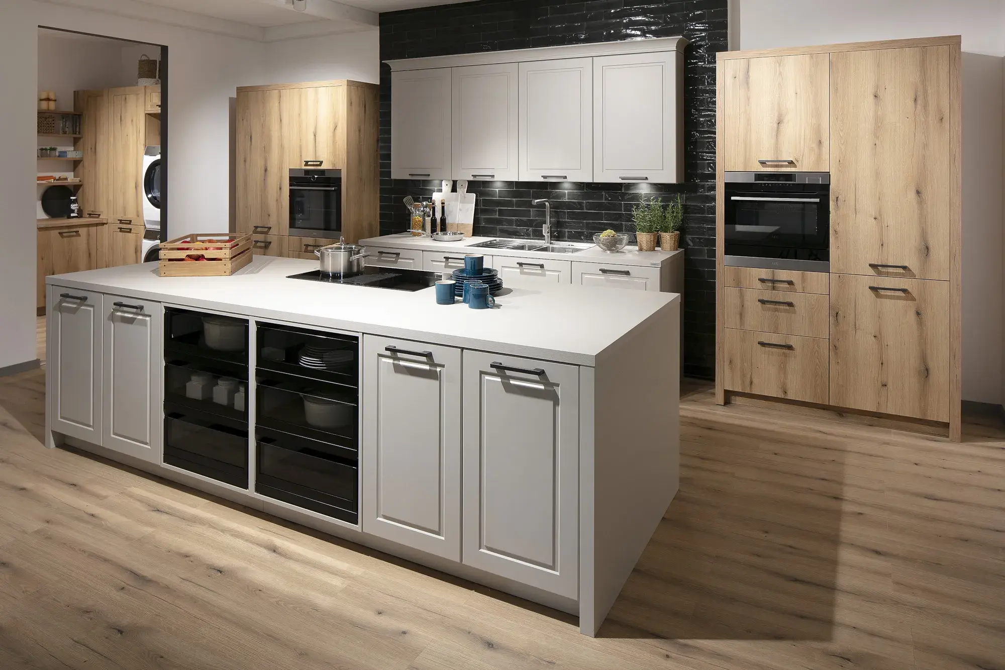 Moderne Küche mit weißer Kochinsel, Holzschränken und schwarzer Fliesenrückwand.